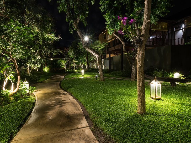 walking path behind home with outdoor lighting fixtures and lit path at night