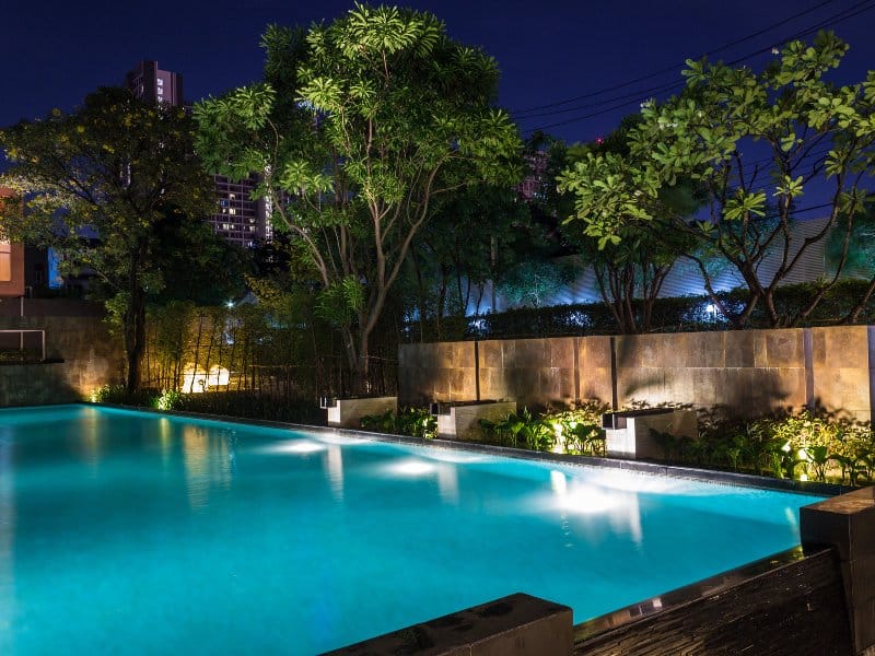 A nighttime view of a beautifully lit outdoor space, featuring a wooden deck