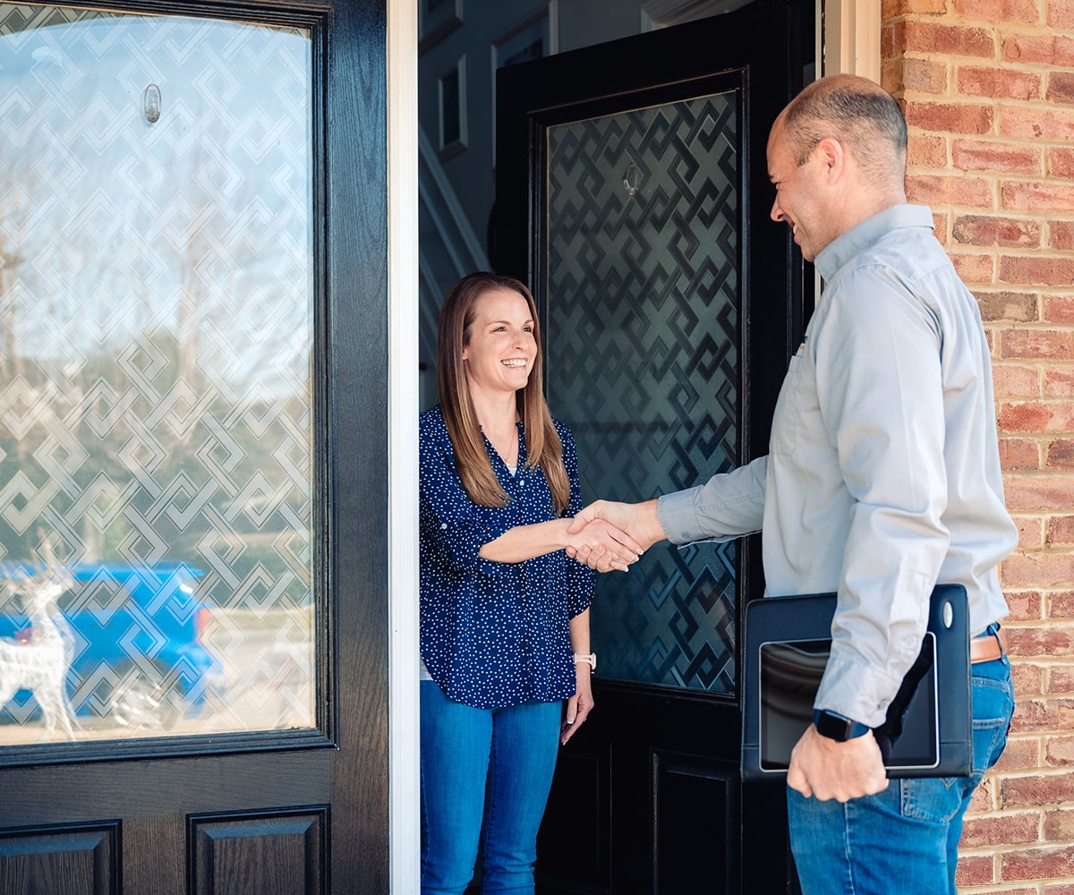 Triad electrician and customer outside of door handshaking